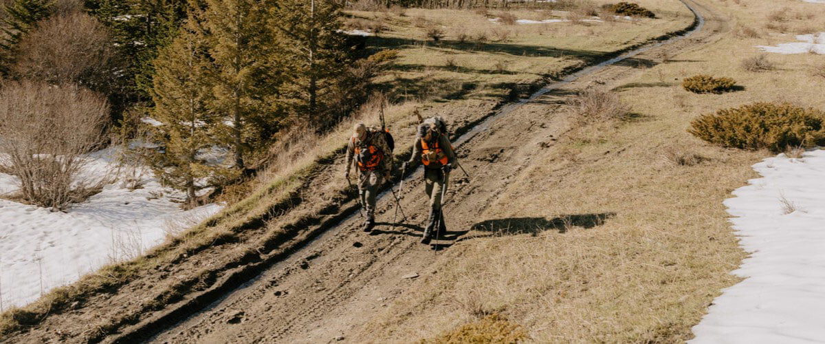 two hunters walking down a dirt road